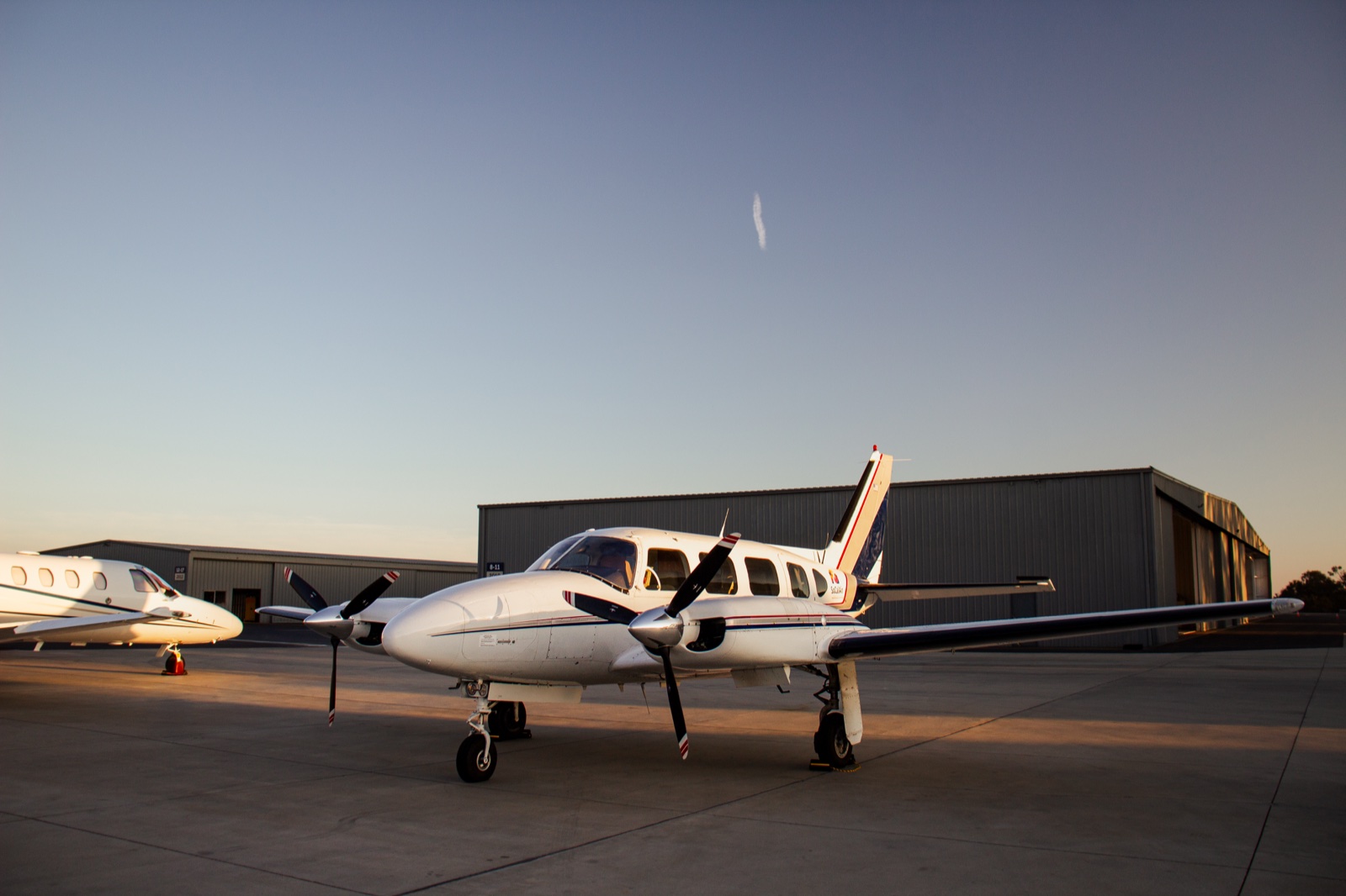 Twin-engine piston aircraft on the apron at sunset